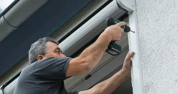 Technicien fixant le coffre d'un volet roulant à la visseuse
